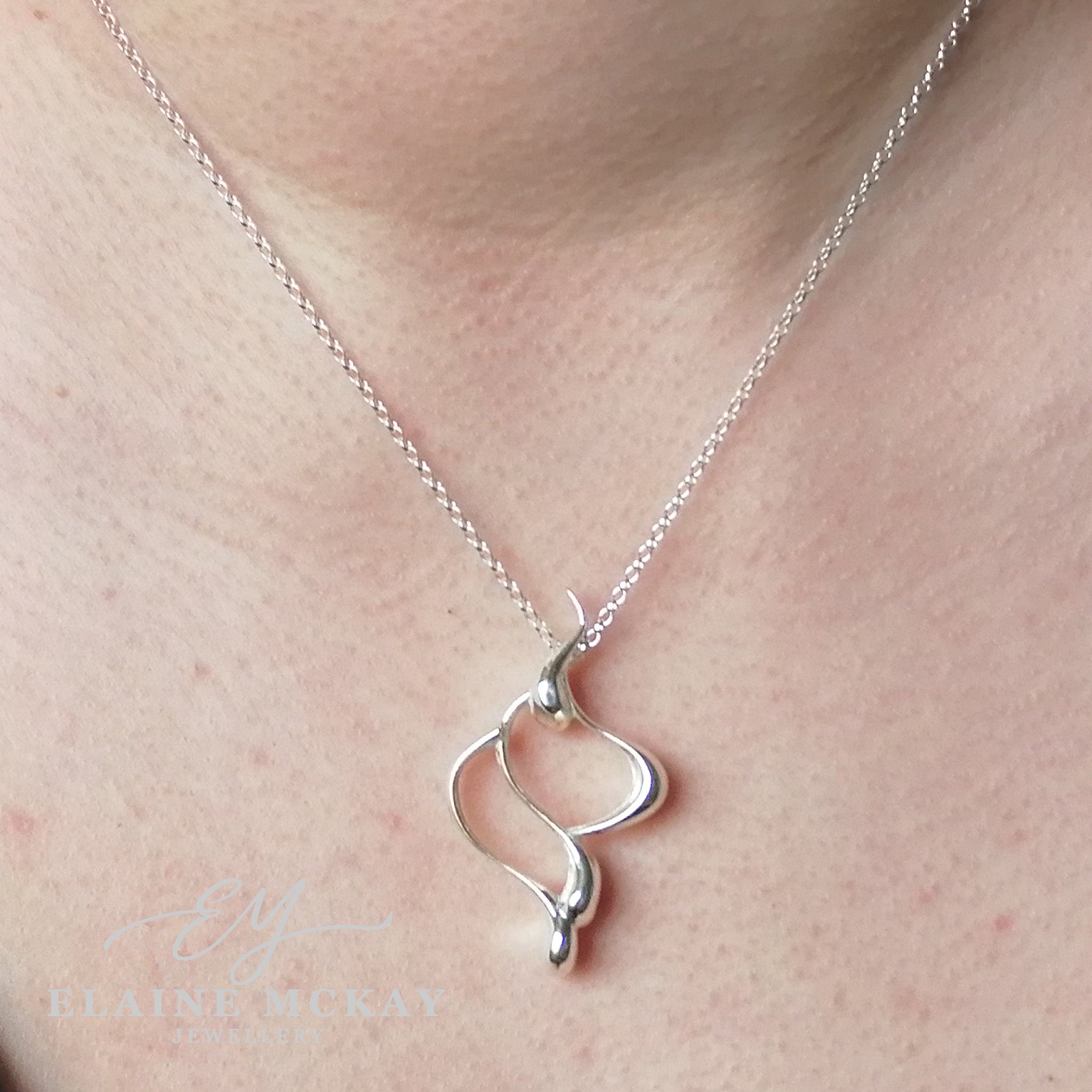 Silver necklace with a unique wave pendant on a person's neck, brand Elaine McKay jewellery.
