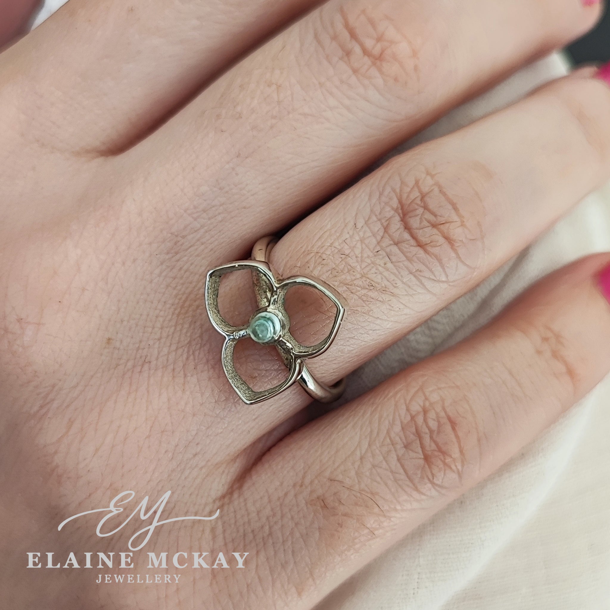 Silver ring with a central bullet shaped topaz gemstone on a person's finger, branded 'Elaine McKay Jewellery