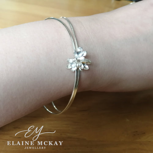 Silver bracelet with a floral design on a wrist, branded 'Elaine McKay Jewellery'.