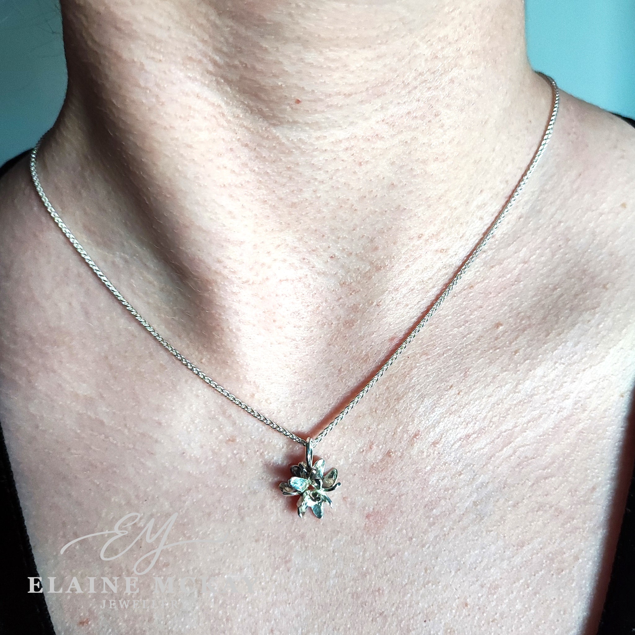 Necklace with a floral pendant on a person's neck against a light background