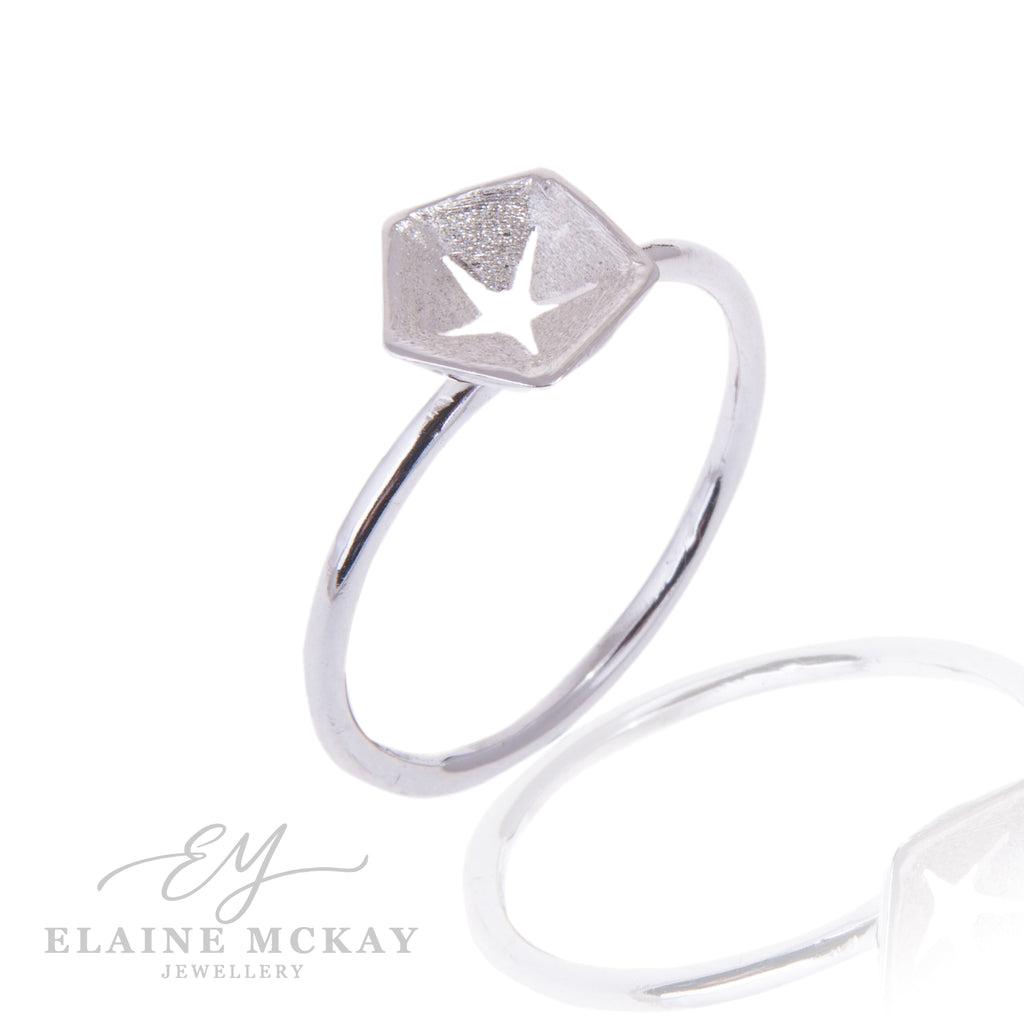 Hex silver ring with a star pierced out of center on a white background