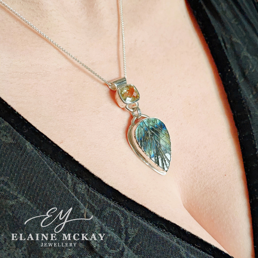 Silver necklace with lemon quartz and a leaf-shaped Labradorite pendant on a person's neck, branded 'Elaine McKay Jewellery'