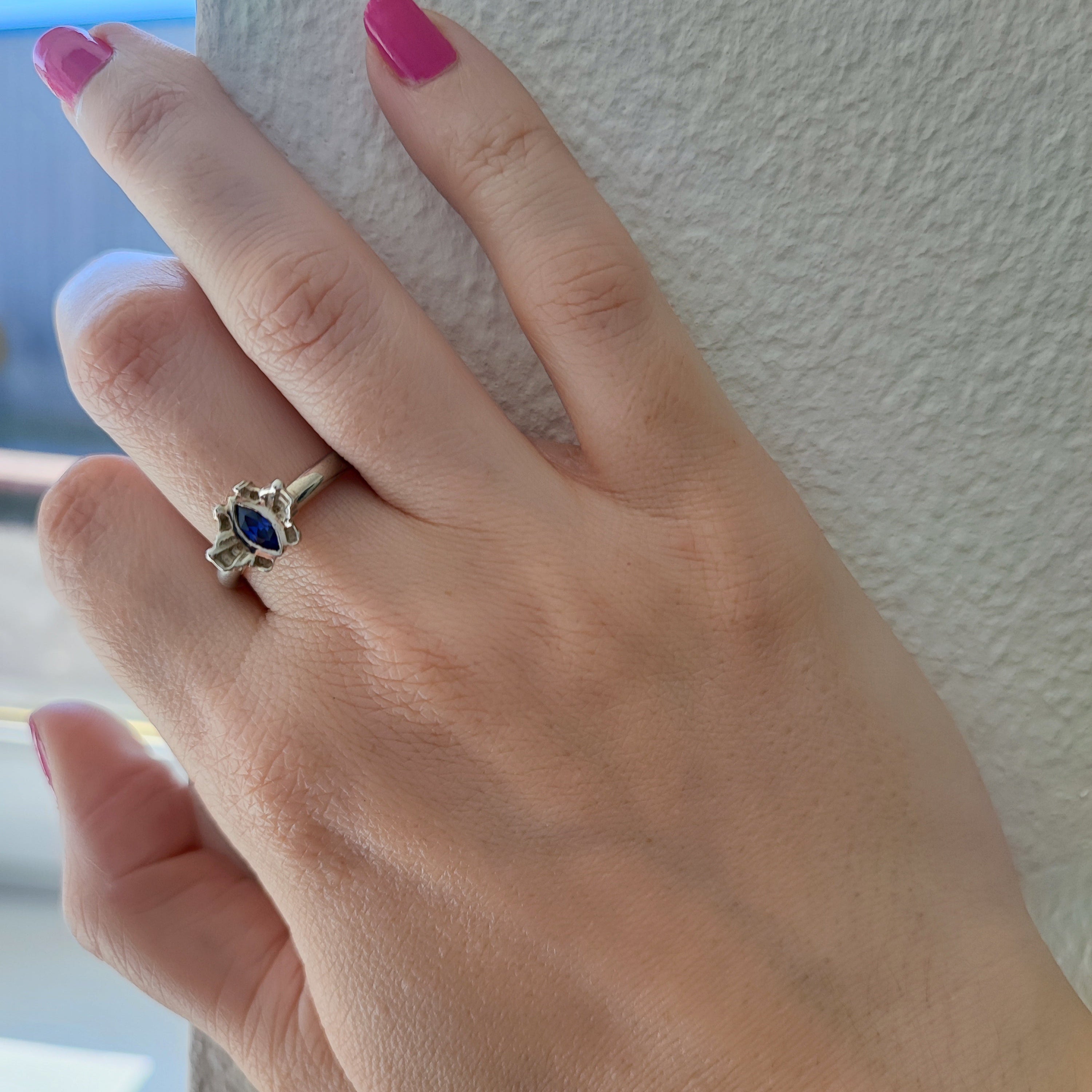 model wearing a silver ring with a tanzanite cubic zirconia gemstone against a neutral background